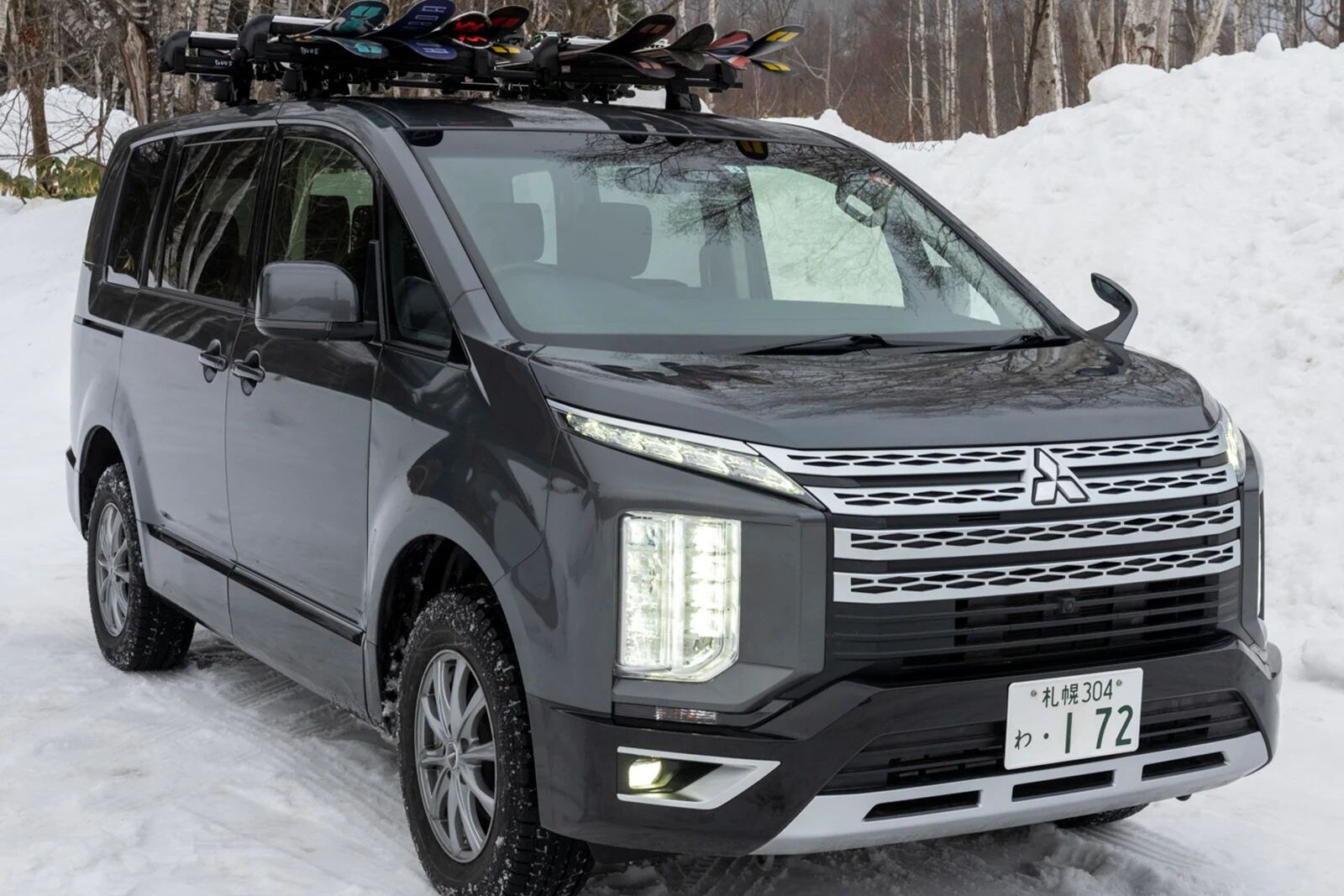 Тёмно-серый Mitsubishi Delica D:5 с лыжами на крыше на заснеженной дороге